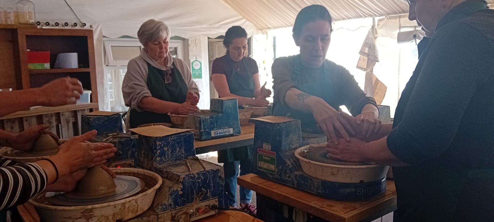 Close-up of hands shaping clay on multiple pottery wheels side by side