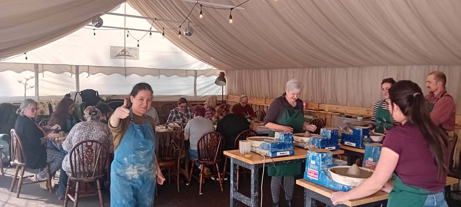 Wide view of a pottery workshop in the marquee with wheels and hand-building tables