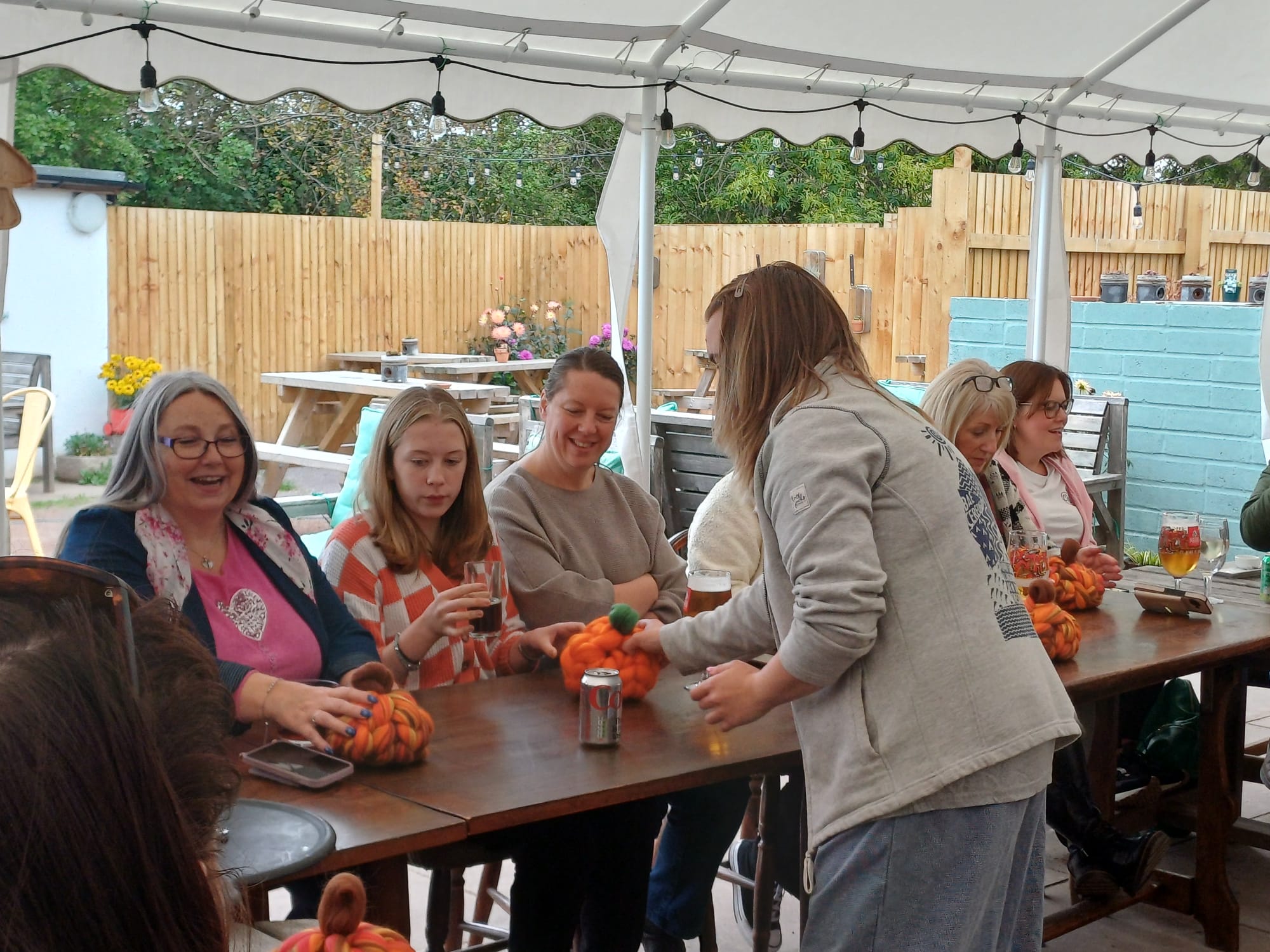 Two participants finishing chunky-wool pumpkins on the pub terrace