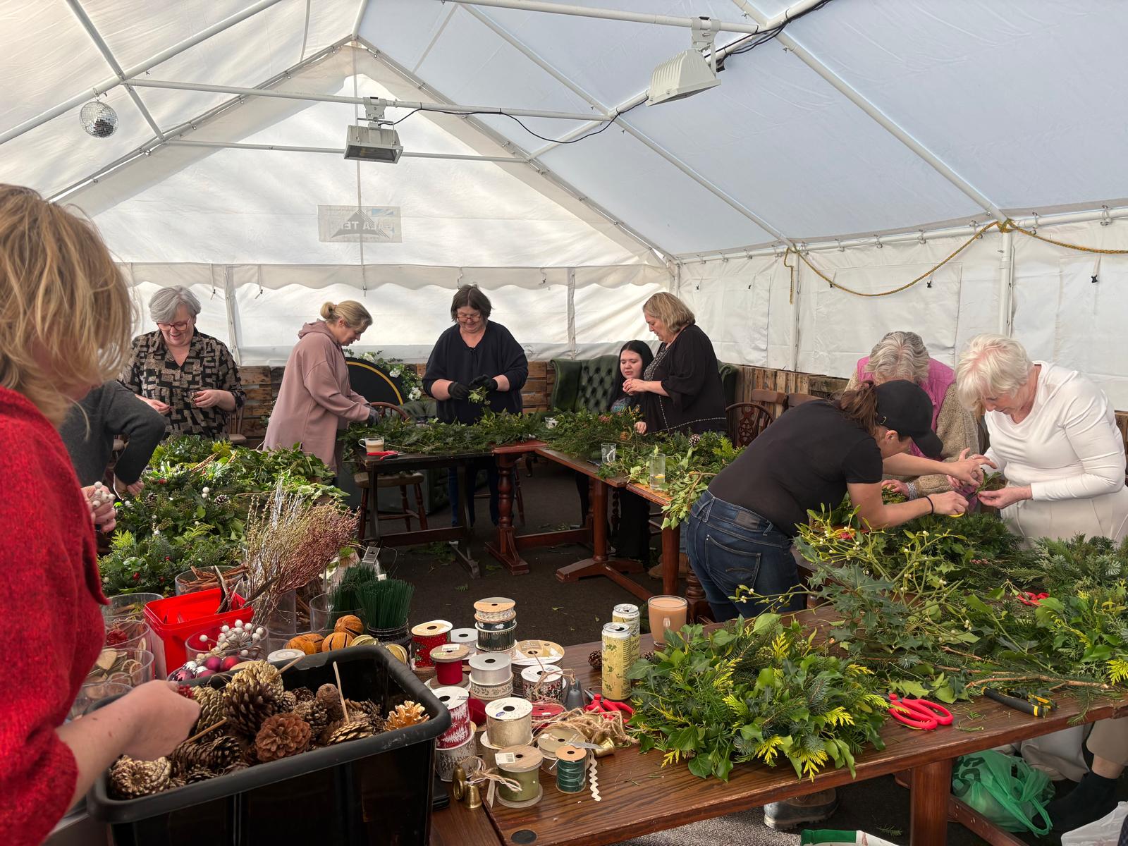 Wide view of the marquee full of people making Christmas wreaths together